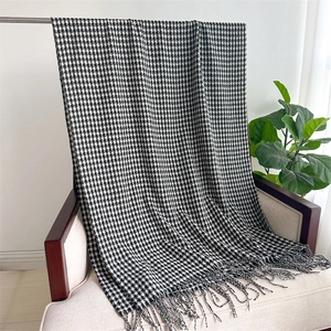 Detail of classic black and white houndstooth scarf with fringe tassels hanging on a chair