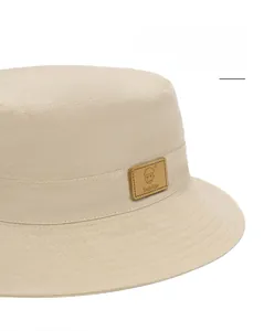 Close-up of wide brim sun hat detail with beige cotton fabric and square leather patch