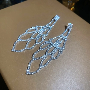Macro detail of silver geometric tassel earrings with glittering pavé rhinestones