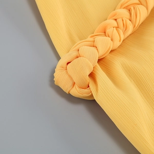 Gros plan détaillé sur un tissu en mousseline jaune avec bordure tressée et texture fine