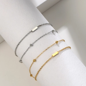 Detail of silver and gold layered bead bracelets wrapped on a white cylinder stand