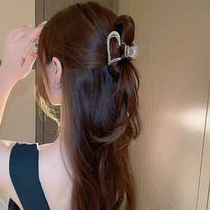 Detailed view of a silver heart-shaped metal hair claw clip worn on a half-up hairstyle