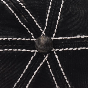 Macro shot of a black baseball cap top button with durable white double stitching details