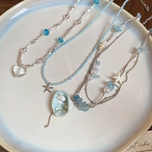 Detail of beach-style necklace featuring starfish, shell, and heart glass bead pendants