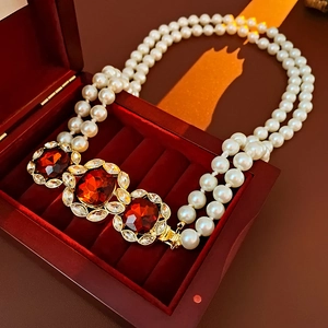Close-up of a double-layer vintage pearl necklace with red gemstones in a velvet box