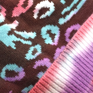 Close-up of tie-dye leopard print knit fabric with thick texture and ribbed edge detail