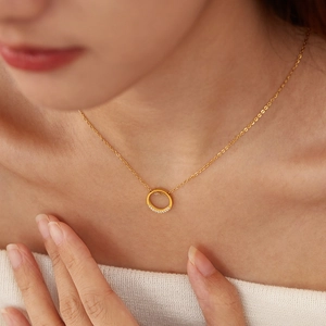 Close-up of a gold-toned circular pendant necklace with inset sparkling zircons on model