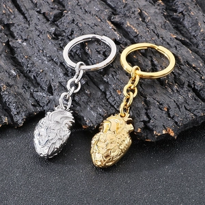 Macro shot of 3D anatomical heart keychains in silver and gold on a dark rock background
