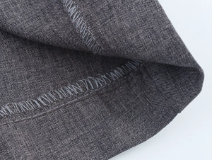 Detail view of dark grey fabric texture with neat overlock stitching on the blazer edge