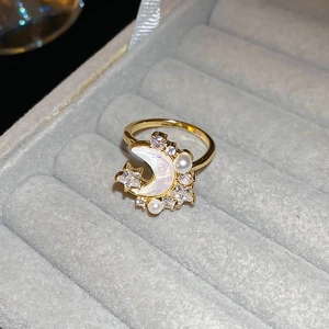 Detailed shot of gold ring featuring star and moon motifs with pearl and zircon accents