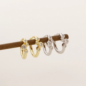 Detailed view of S925 silver hoop earrings with cubic zirconia on a wooden stand