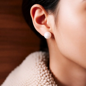 Close-up of a model wearing a minimalist round white pearl stud earring with high luster