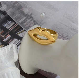 Close-up of a 18K gold plated lip-shaped ring on a white stand with blurred background