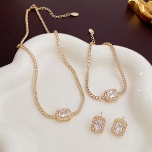 Detail view of gold jewelry set with square zircon crystals on white cloud tray
