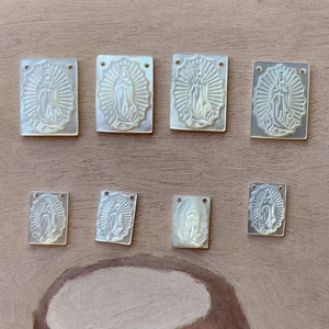 Macro view of eight rectangular mother of pearl pendants with Virgin Mary carvings