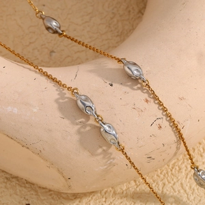 Close-up of gold chain necklace with silver oval beads and small sparkling diamonds