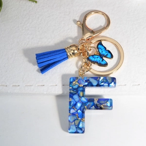 Macro shot of royal blue resin letter F keychain with tassel and butterfly detail