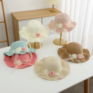 Detail of children's straw hats with lace flowers and wavy edges in multiple colors