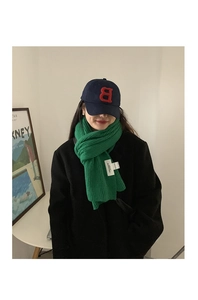 Detail of green thick knit scarf paired with a navy blue baseball cap featuring a B patch