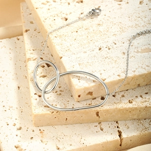 Detail of silver stainless steel double oval loop pendant on a textured stone surface