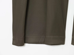 Detailansicht der Einzelnadelstiche und Twill-Stoffstruktur am dunkeloliven Kleidungsstück