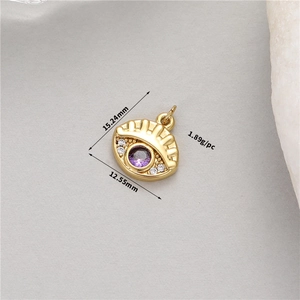 Macro view of 14K gold evil eye charm with size measurements 15.24mm and 12.55mm