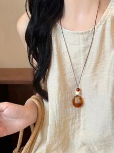 Close-up of retro resin ring pendant on a dark brown cord with ethnic beads