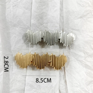 Detail view of gold and silver textured metal hair clips with size 8.5cm by 2.8cm
