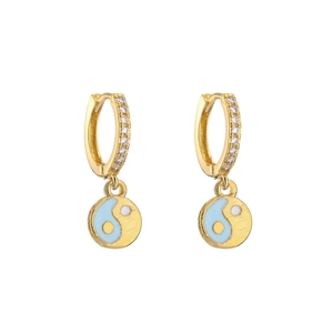 Macro detail of gold-plated hoop earrings with micro-pave zircons and blue yin-yang charm