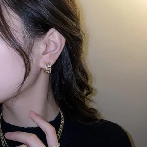 Boucles d'oreilles C géométriques plaquées or avec zircons blancs étincelants sur modèle