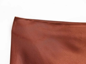 Macro detail of the silk satin fabric with visible twill texture and lace trim in brown