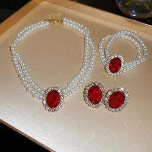 Detail of vintage jewelry set featuring red oval gemstones and double-layer white pearls