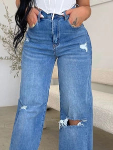 Detail shot of distressed ripped knees on light blue high-waisted wide-leg denim jeans