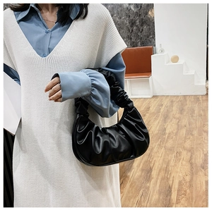 Detail of black ruched cloud bag showing the pleat texture and modern crescent shape