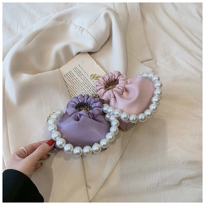 Close-up of pink and purple pleated pearl handle handbags for girls on a blazer