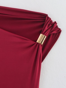 Detailed close-up of golden metal buckle and ruched fabric on red one-shoulder top