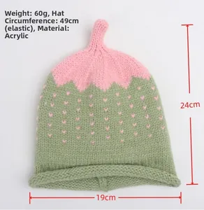 Flat lay of pink and green knitted hat with strawberry sprout top and size markings