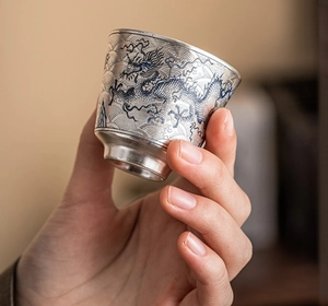 Primer plano detallado de una taza de té plateada con intrincados patrones de dragón