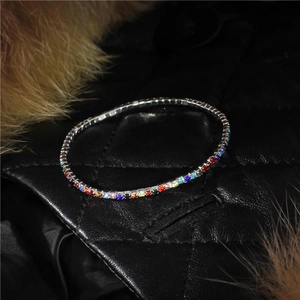 Macro shot of 2mm rainbow rhinestone tennis bracelet on black quilted leather background