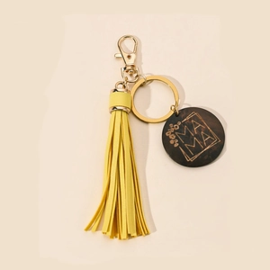 Detail of wooden MAMA charm with yellow tassel on a stylish PU leather keychain