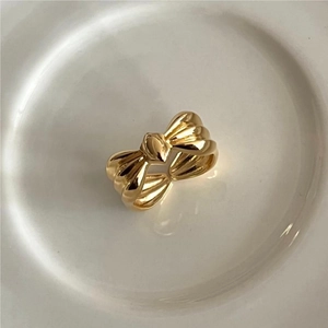 Minimalist 925 sterling silver bow ring in golden finish on a ceramic plate