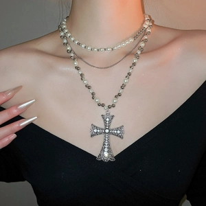 Detail of elegant multi-layer silver necklace with crystal cross pendant and pearls