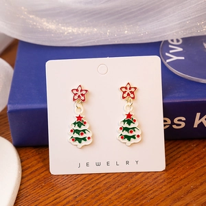 Detailed view of Christmas tree earrings with red stars on a white jewelry card