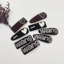 Close-up of velvet hair clips with rhinestone WANG and CHANCE lettering in black and burgundy