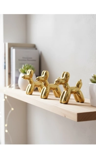 Dettaglio di tre sculture a forma di cane palloncino dorato con finitura a specchio