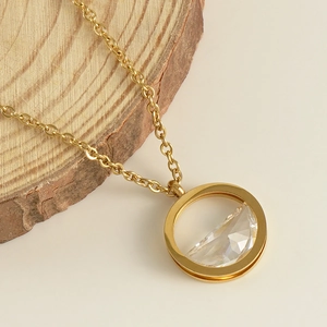 Detailed close-up of golden ring pendant featuring a faceted clear crystal on O-chain
