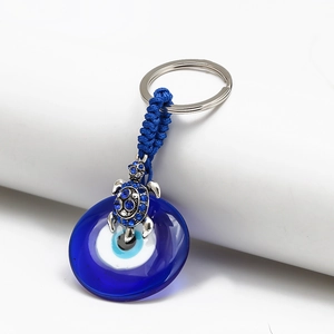 Detailed view of silver turtle pendant with blue rhinestones and glass evil eye charm