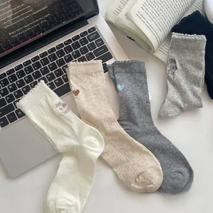 Detail of knit crew socks with colorful heart embroidery and 'She is Kind' text