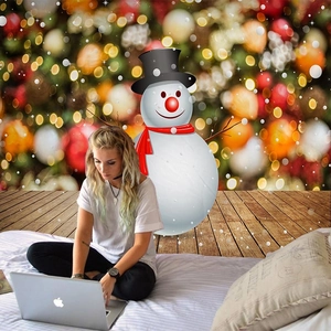 Christmas wall tapestry with snowman and golden bokeh lights behind a person using laptop