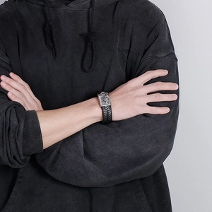 Detailed shot of men's leather braided bracelet featuring a silver skull metal plate